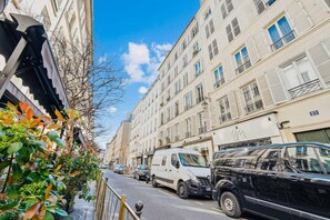 Una vista di strada con auto parcheggiate, un furgone bianco e un'auto nera.