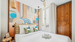 A hotel room with a large bed, a wooden wardrobe, and a wall with abstract art. - Appartement Central 2bdr - 6P le Marais (Paris)