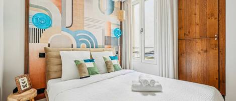 Una habitación de hotel con una cama grande, un armario de madera y una pared con arte abstracto.