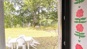 A window with a view of a grassy yard, a white table, and chairs.