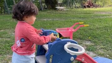 Un bambino gioca con un trattore giocattolo in un'area erbosa all'aperto.