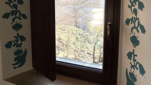A room with a window, a door, and a view of trees outside.