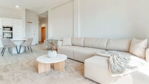 Un soggiorno moderno con un divano beige, un tavolino rotondo e un'area pranzo con sedie e tavolo.
