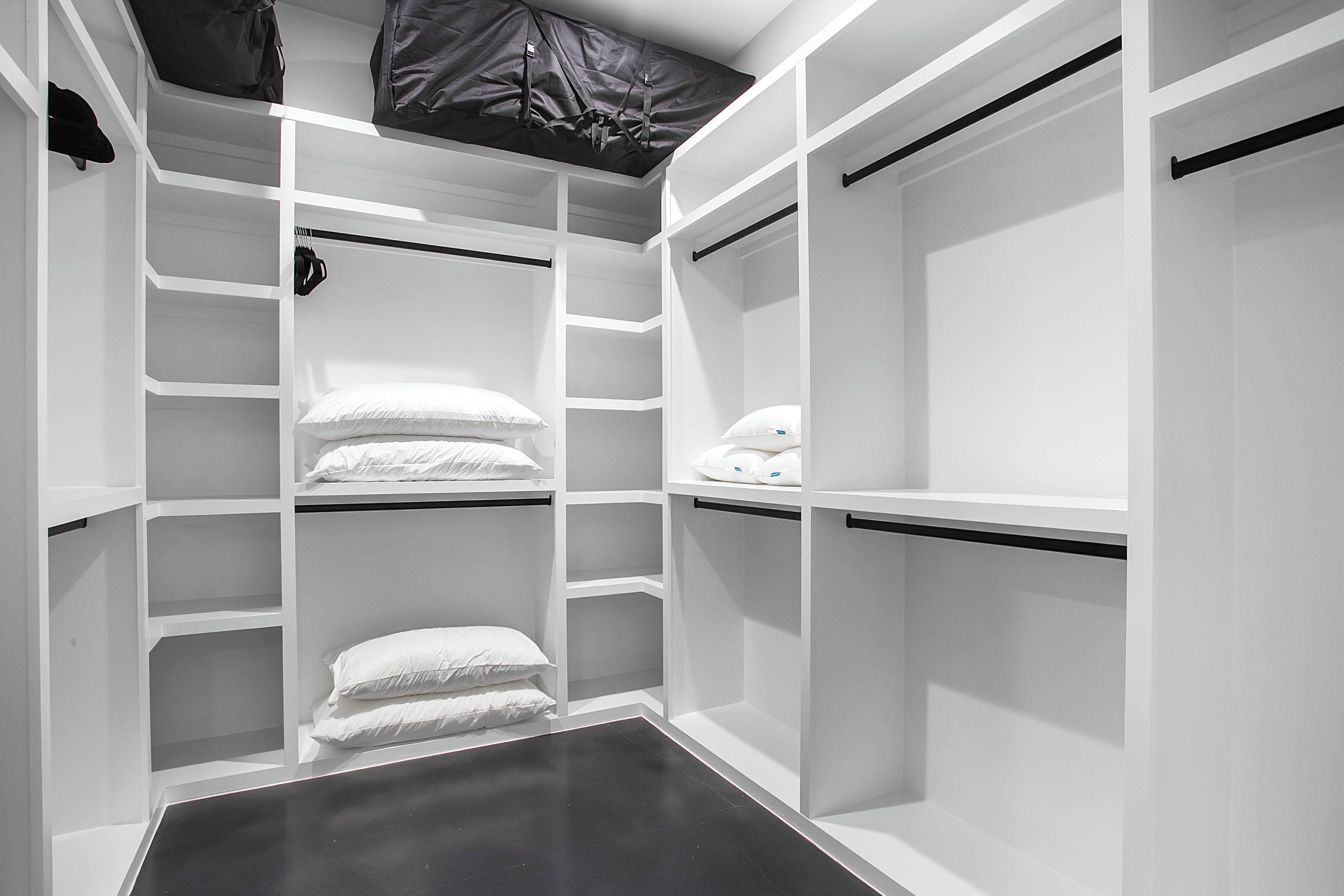 Un vestidor con estanterías blancas y suelo negro.