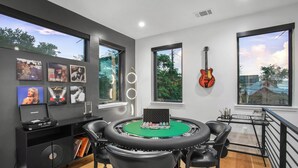 A modern room with a round table, black leather chairs, a guitar, and framed pictures on the wall. - ATX South Lamar Creekside with Hot tub (Austin)