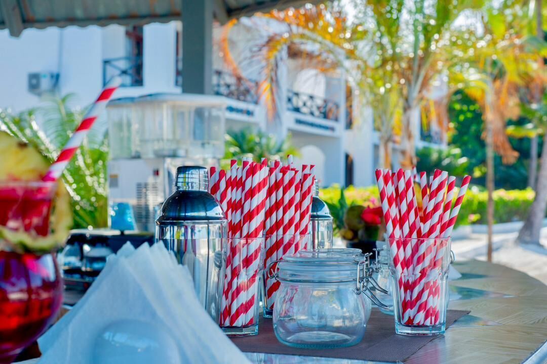 A table with clear glass mugs, a metal shaker, and a glass with a straw.