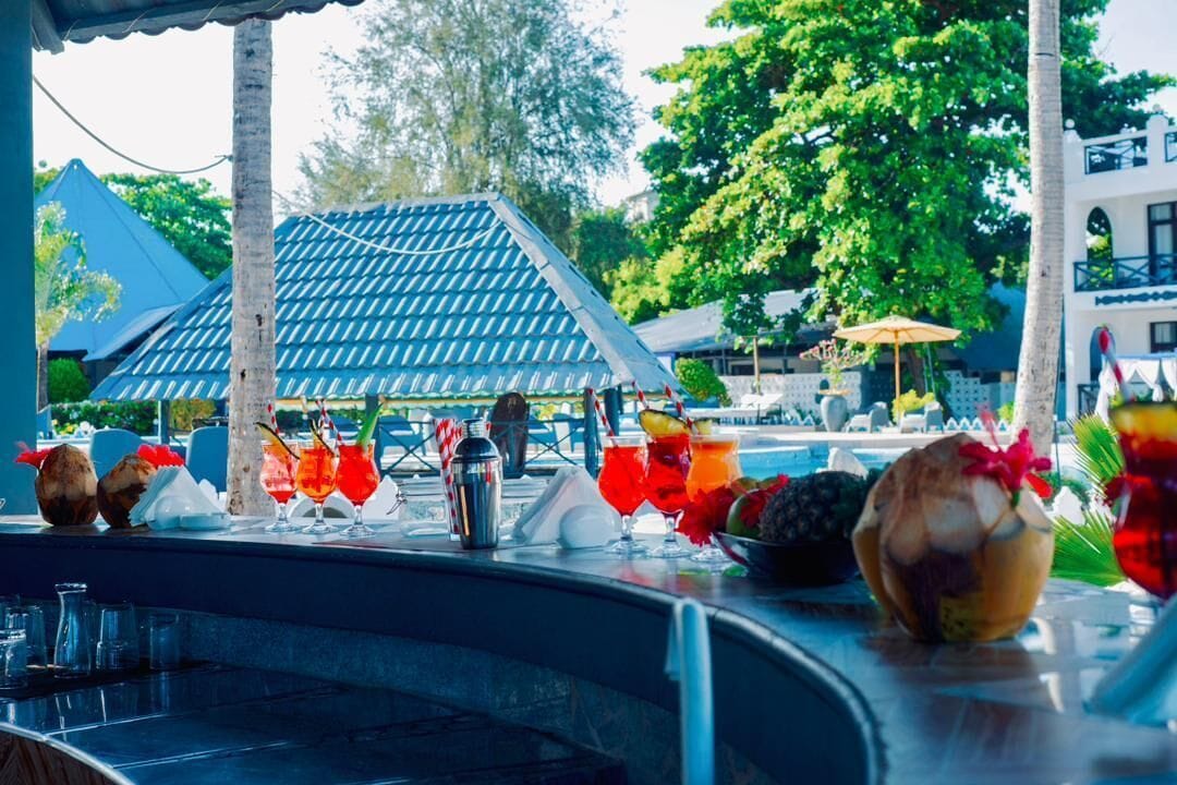 Un espace bar avec vue sur la piscine, comprenant une structure de toit en carrelage et une piscine.