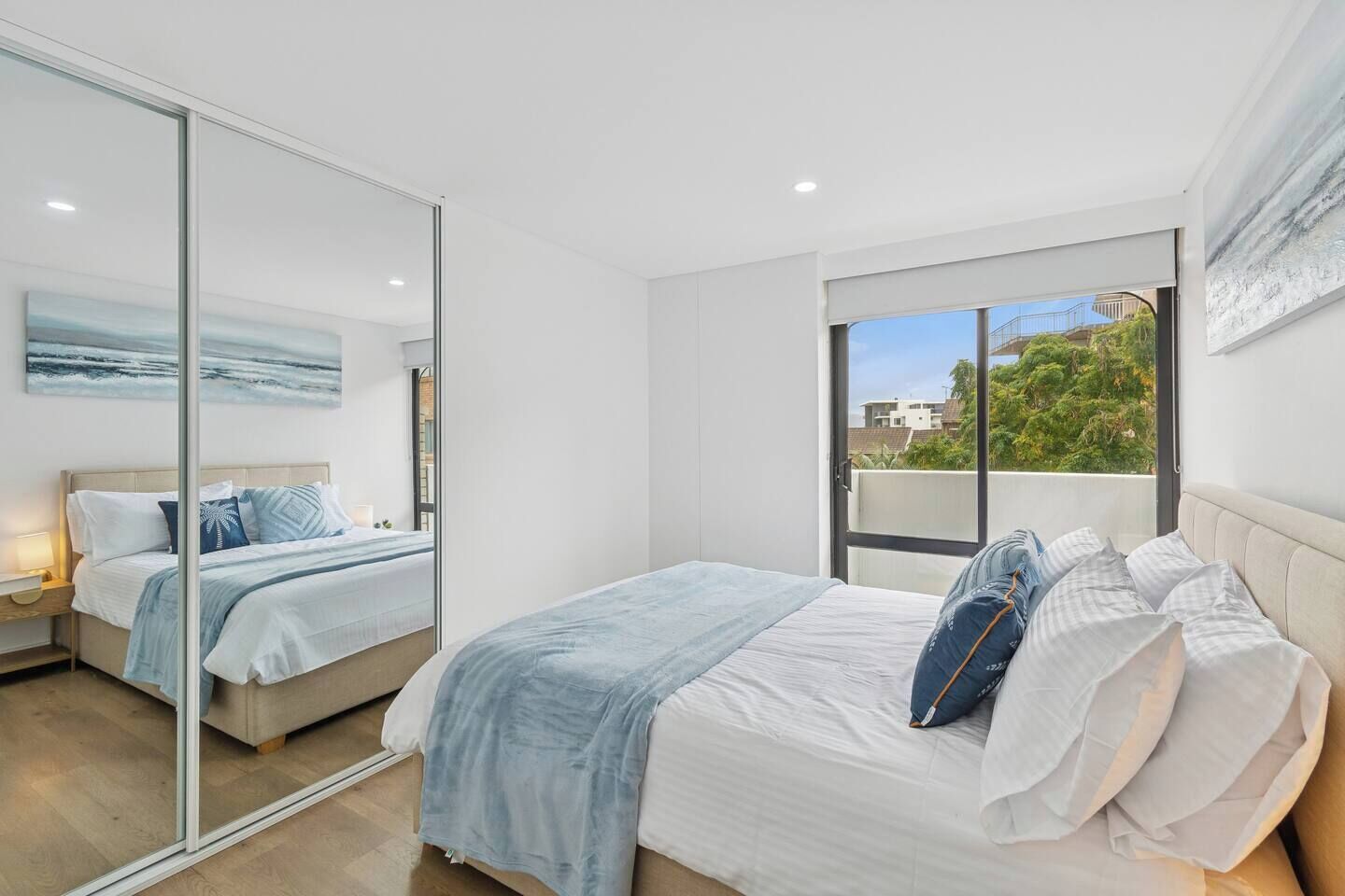 Rest easy in the primary bedroom featuring a queen bed, tranquil blue details, a built-in mirrored wardrobe, and private balcony access.