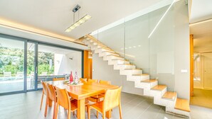 A modern dining area with a wooden table and chairs, a glass staircase, and a view of the outdoors. - Villa Alzina house with pool in Majorca (Sa Pobla)