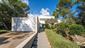 A modern building with a concrete pathway leading to a glass entrance. - Villa Alzina house with pool in Majorca (Sa Pobla)