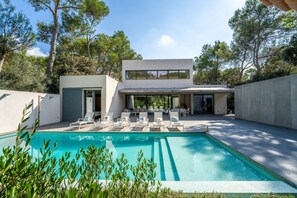 Una casa moderna con piscina, mobiliario exterior y zona de patio.