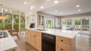 A spacious kitchen with a large island, built-in cabinetry, and a dishwasher. - Luxury Sea Pines Retreat w/ Pool & Golf Views (Hilton Head Island)