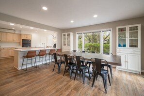 Una cocina moderna con una isla central, taburetes de bar y un comedor con sillas.