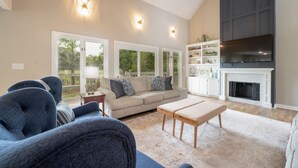 A living room with a sofa, a coffee table, a fireplace, and a TV. - Luxury Sea Pines Retreat w/ Pool & Golf Views (Hilton Head Island)