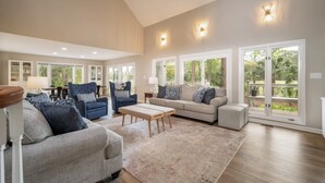 A spacious living room with a high ceiling, large windows, and a view of the outdoors. - Luxury Sea Pines Retreat w/ Pool & Golf Views (Hilton Head Island)