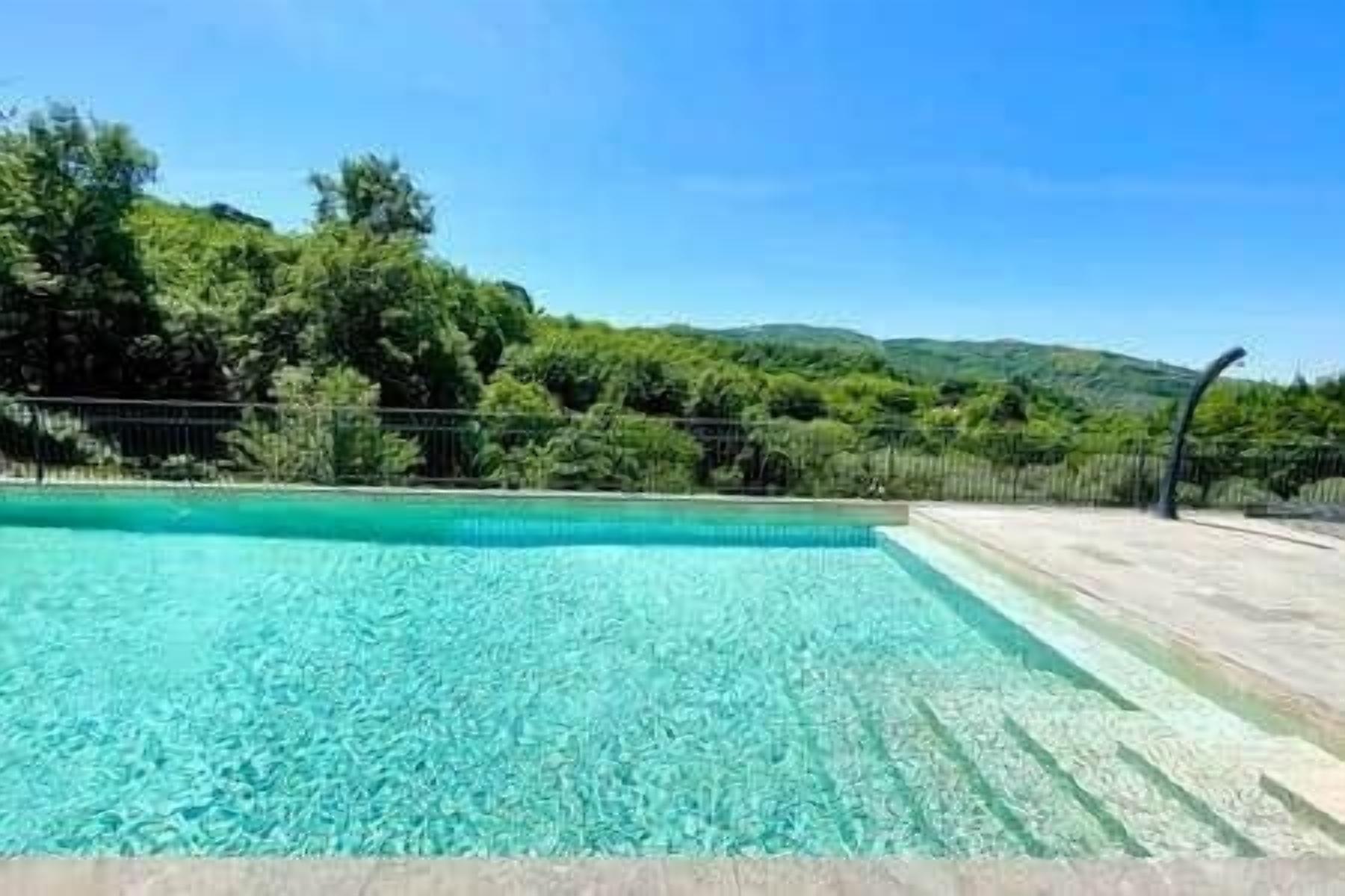 Una piscina cristallina con vista su una rigogliosa vegetazione e dolci colline sullo sfondo.