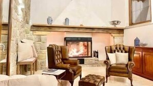 A cozy living room with a fireplace, stone walls, and wooden furniture. - Luxury Villa Podere Del Grasso, Tuscany, ITALY (Castel del Piano)