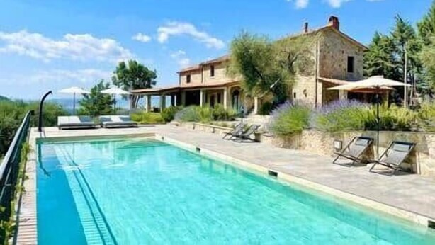 A pool with lounge chairs, a stone building, and a clear sky. - Luxury Villa Podere Del Grasso, Tuscany, ITALY (Castel del Piano)