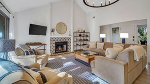 A modern living room with a fireplace, sofas, a coffee table, and a TV. - Chic Hilton Head Getaway in Heart of Sea Pines (Hilton Head Island)