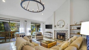 A spacious living room with a fireplace, a large sofa set, a coffee table, and a television mounted on the wall. - Chic Hilton Head Getaway in Heart of Sea Pines (Hilton Head Island)