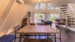 Een eethoek met een houten tafel en stoelen, een trap en uitzicht op het omliggende landschap.