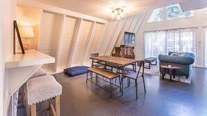Een kamer in loftstijl met een eettafel, bankjes, een bank en een televisie.