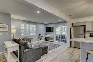 A modern living room with a grey sofa, a white coffee table, and a TV mounted on the wall.