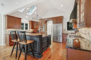A spacious kitchen with wooden cabinets, a central island, and a skylight.