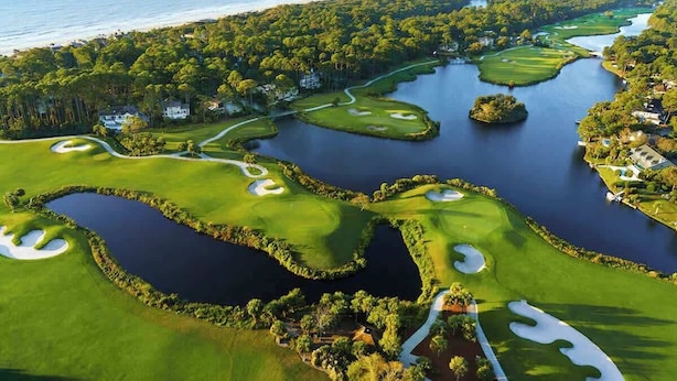 A golf course with water hazards, sand bunkers, and a view of the ocean.