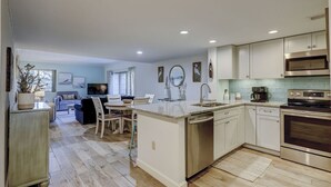 Una cocina moderna con una isla central, electrodomésticos de acero inoxidable y un comedor con vistas.