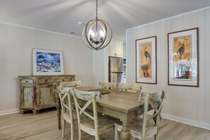 A dining room with a wooden table and chairs, a chandelier, and framed artwork on the walls.