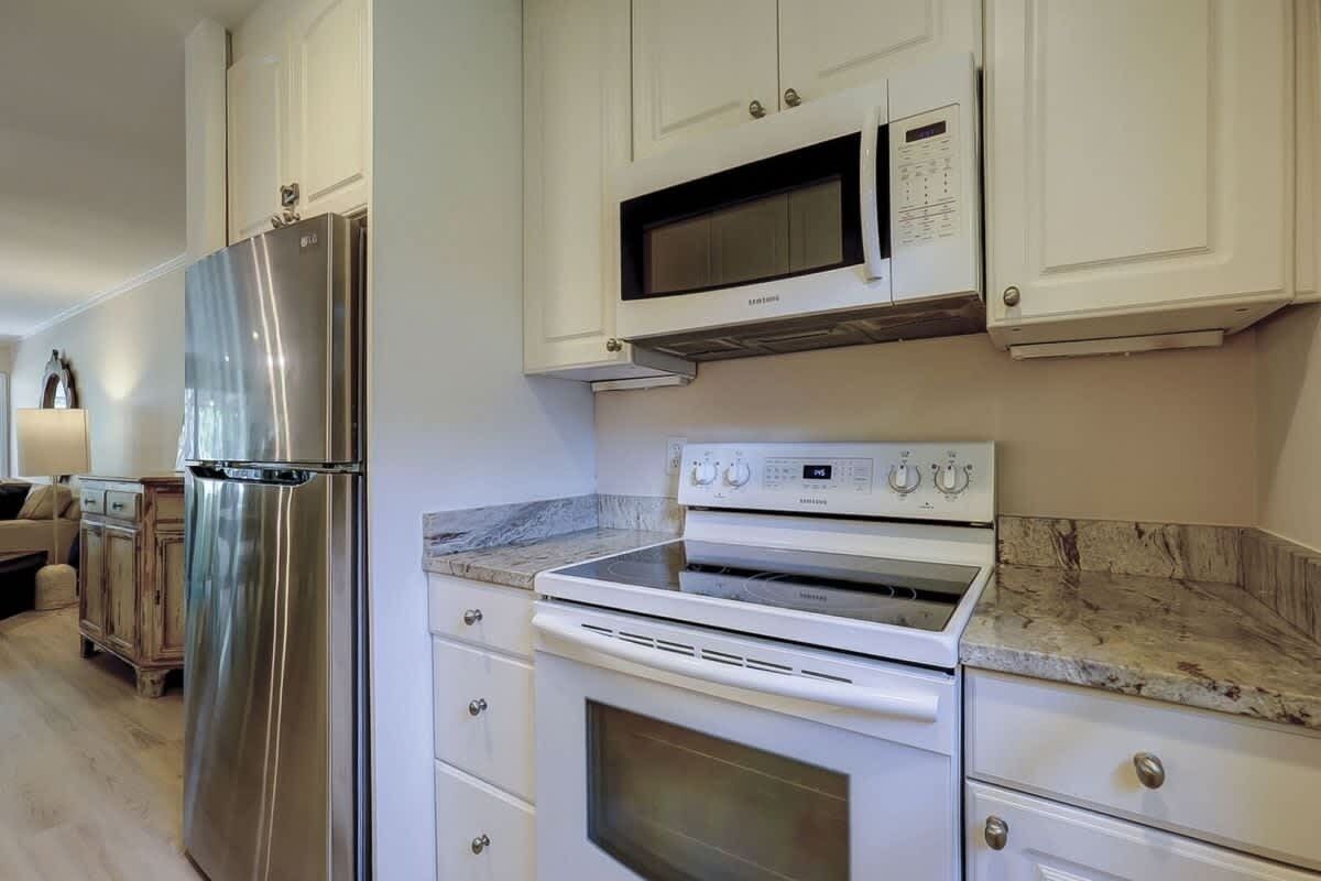 A kitchen with a stainless steel refrigerator, a microwave, and a white oven.