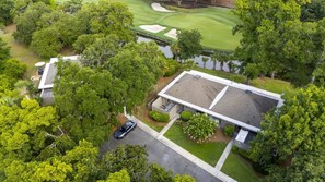 A residential property with a large house, a driveway, and a golf course in the background.