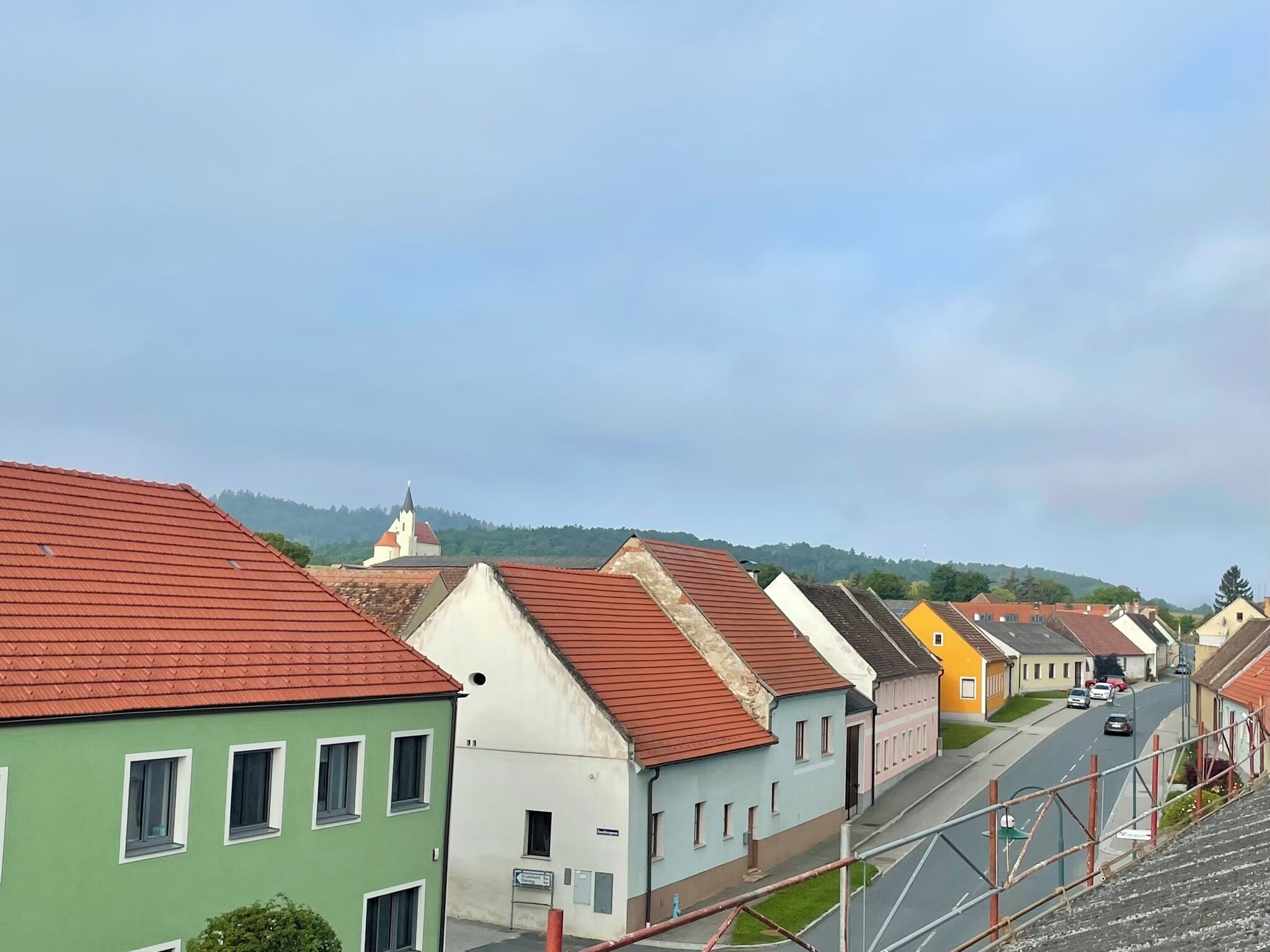 Eine Reihe bunter Häuser mit roten Dächern und einer Kirche im Hintergrund.