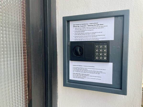 Quiosco de auto check-in con instrucciones en varios idiomas, un teclado y una llave pequeña para acceder a la habitación.