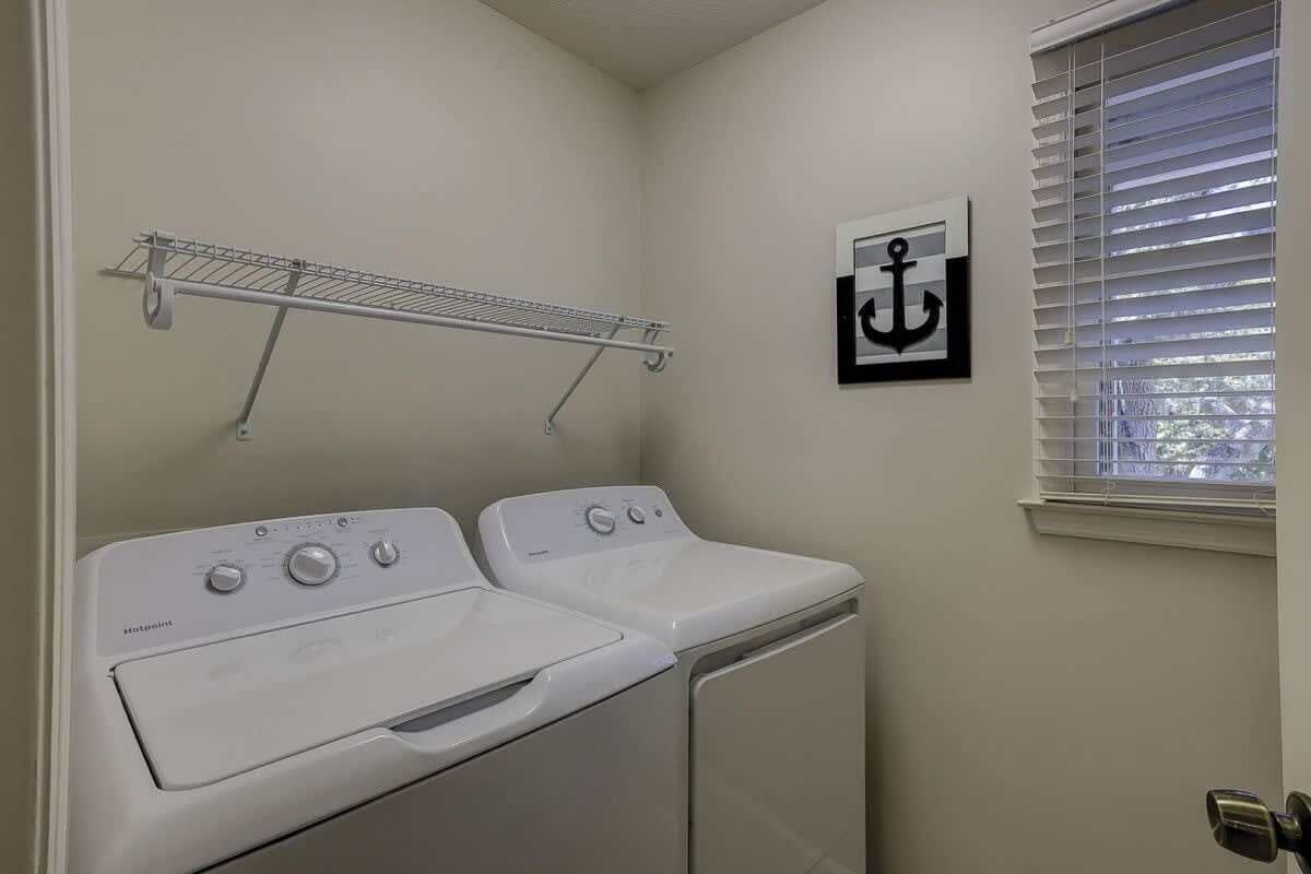 Un cuarto de lavandería con dos lavadoras apiladas y un tendedero.