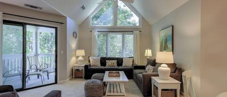 A living room with a ceiling fan, two couches, a coffee table, and a large window with blinds.