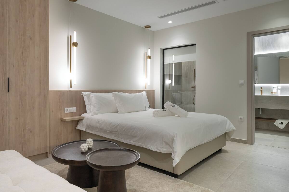 A modern bedroom with a large bed, bedside tables, and a walk-in closet.