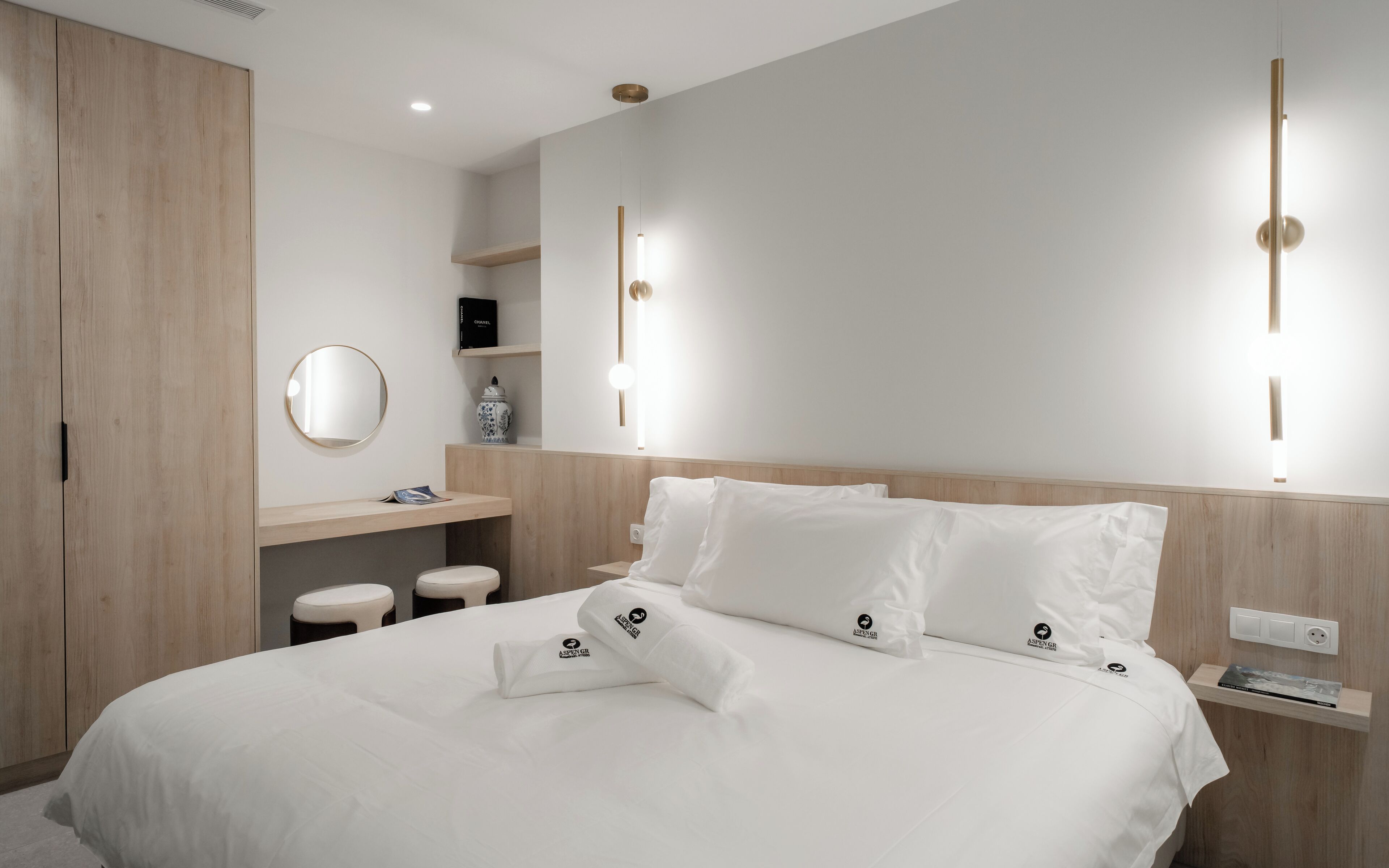 A modern bedroom with a large bed, bedside tables, a wardrobe, and a mirror.