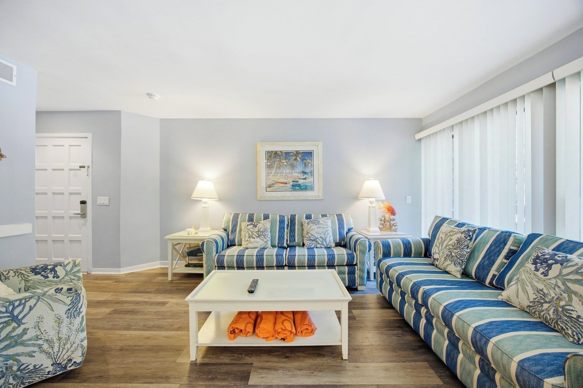 A living room with striped sofas, a white coffee table, and a painting on the wall.