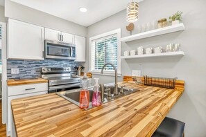 Una cocina moderna con armarios blancos, un microondas, un horno, un fregadero y encimeras de madera.