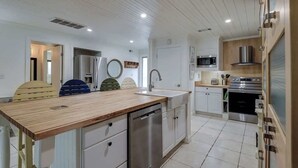 Eine Küche mit Holzausziehtisch, Edelstahlgeräten und weißen Schränken.
