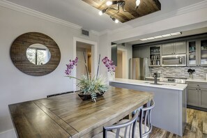 Une cuisine moderne avec une table à manger en bois, un grand miroir et une plante en pot.