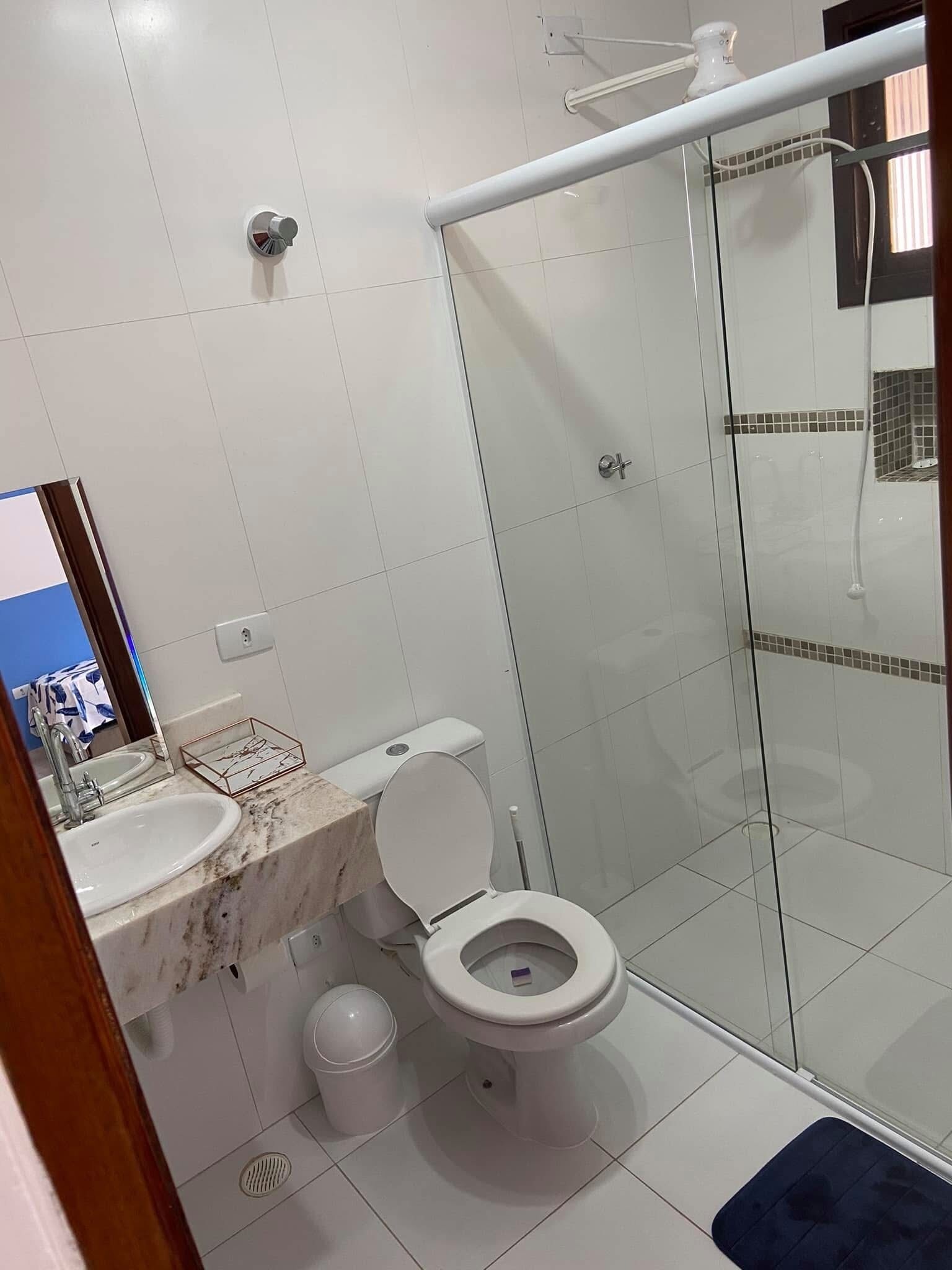 Et badeværelse med toilet, håndvask og bruseområde.
