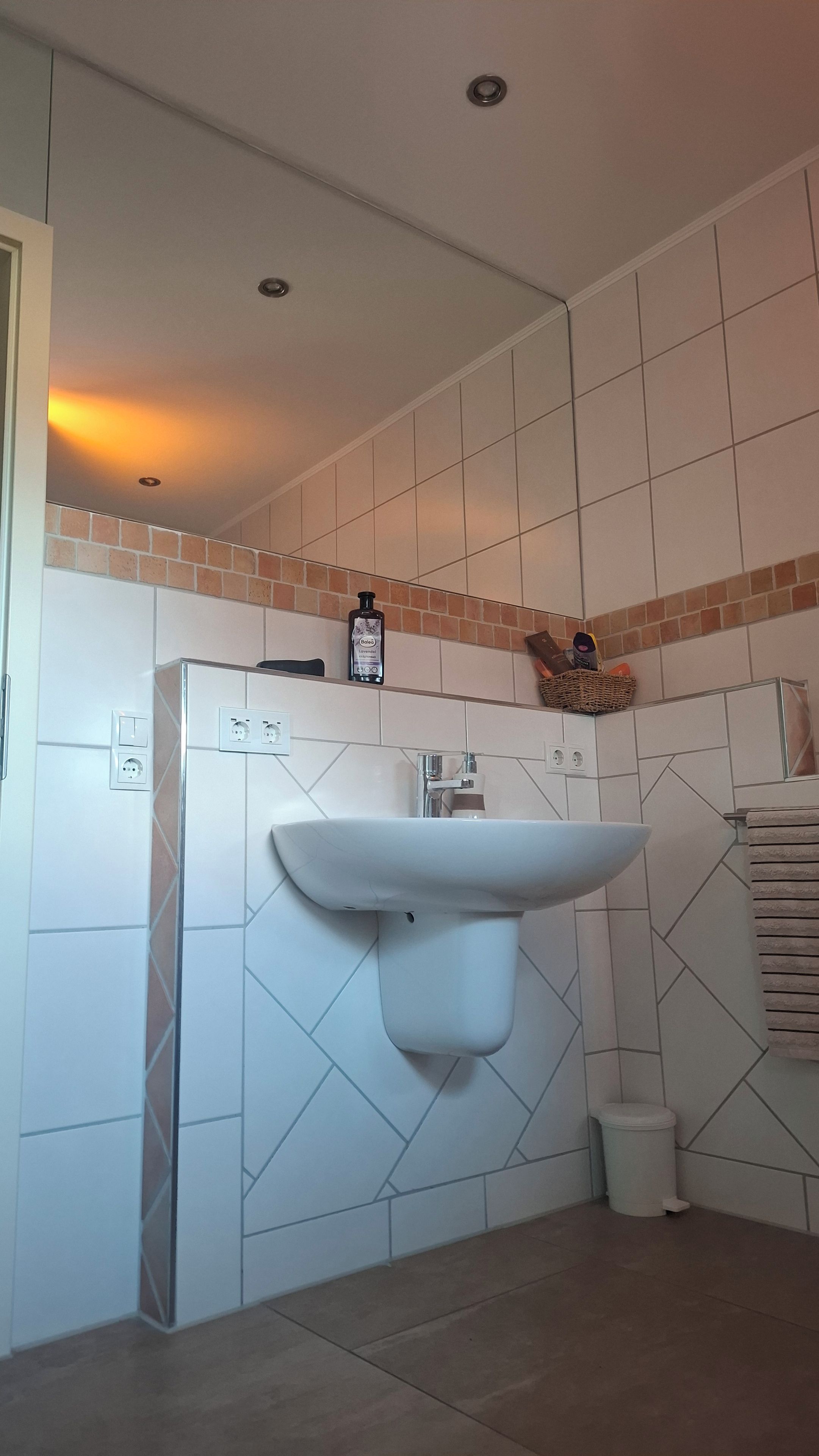 Un baño con un lavabo blanco, un espejo y un perchero para toallas.