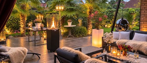 An outdoor patio with seating, a fire feature, and ambient lighting.