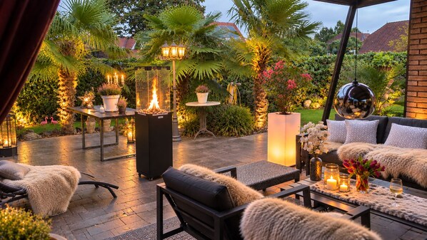 An outdoor patio with seating, a fire feature, and ambient lighting.