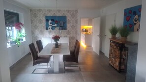 A modern dining area with a white table, dark chairs, and a vase of flowers.