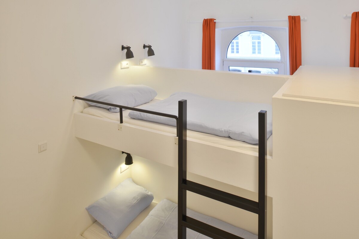 A bunk bed room with a window and two wall-mounted reading lamps.