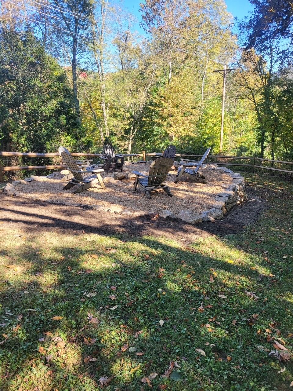 Un área de estar al aire libre con sillas Adirondack y una fogata.